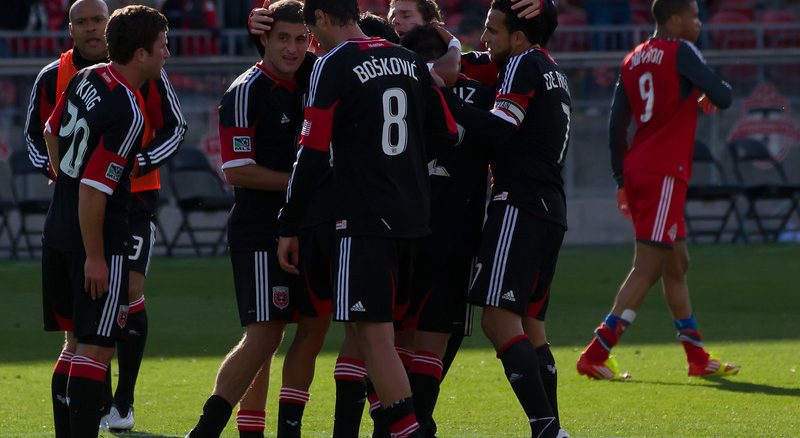DC United Captain Dwayne De Rosario celebrates a 2-0 win with his teammates against his old team at BMO Field. In the background frustrated Toronto FC forward Ryan Johnson walks off the pitch (JP Dhanoa)